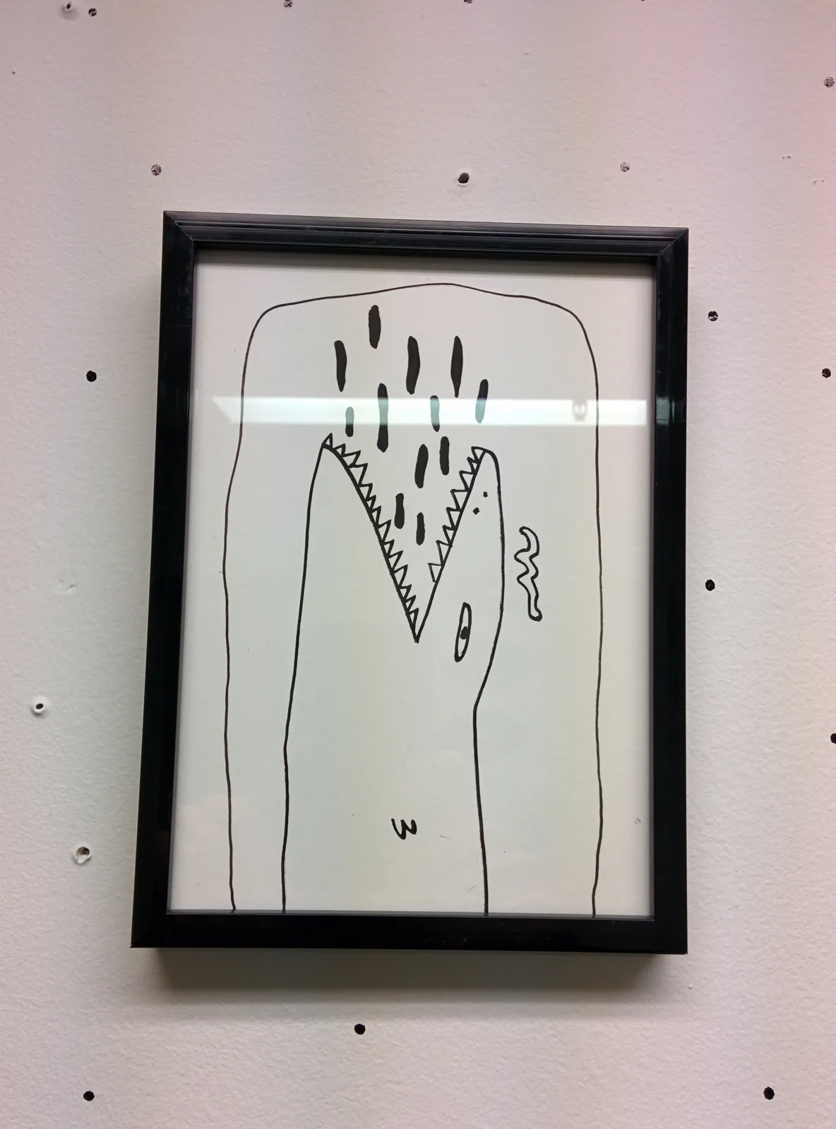 Dessin encadré : tête de varan de profil, gueule grande ouverte sur des mâchoires en dents de scie, œil ovale et langue ondulée, feutre noir sur papier clair