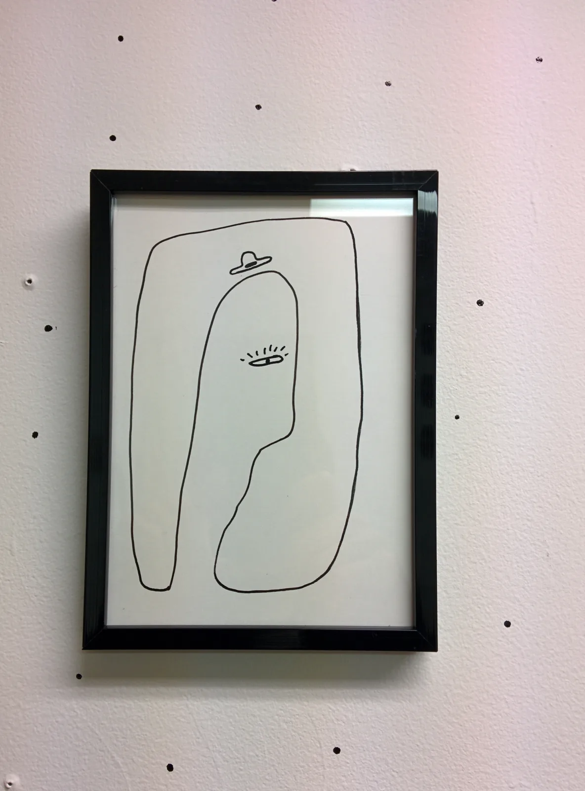 Dessin encadré : silhouette allongée coiffée d'un petit chapeau flottant, un œil clos souligné de cils, le tout enfermé dans un second contour